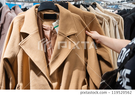 Customer Hand Picking Coat from Clothing Rack in Store 119520562