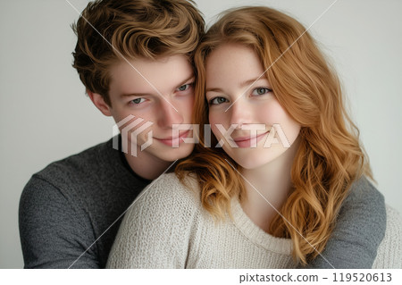 Young couple sharing a warm embrace in a cozy indoor setting during daytime, showcasing affection 119520613