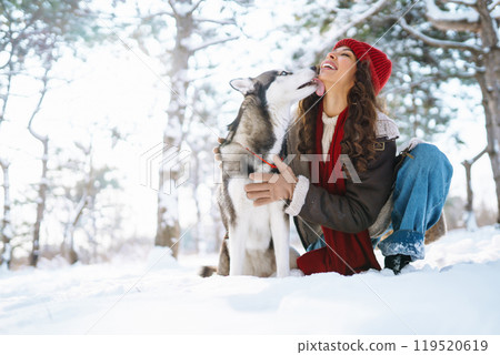 Young woman walking her dog in winter and both explore the snow together in playful mood. Friendship Young woman walking her dog in winter and both explore the snow together in playful mood. Friendship 119520619
