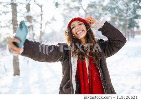 Smiling young woman taking selfie in winter forest. Winter holiday. 119520621