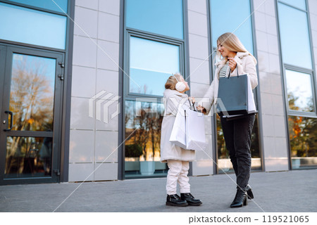 Young mother and little girl with shopping bags after shopping. Spring Style. Consumerism. Young mother and little girl with shopping bags after shopping. Spring Style. Consumerism. 119521065