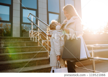 Young mother and little girl with shopping bags after shopping. Spring Style. Consumerism. Young mother and little girl with shopping bags after shopping. Spring Style. Consumerism. 119521066