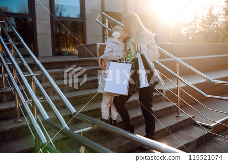 Young mother and little girl with shopping bags after shopping. Spring Style. Consumerism. Young mother and little girl with shopping bags after shopping. Spring Style. Consumerism. 119521074