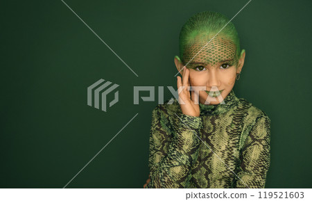 A beautiful elegant teenage girl with makeup imitating the texture of snakeskin on a green studio background. The symbol of 2025 A beautiful elegant teenage girl with makeup imitating the texture of snakeskin on a green studio background. The symbol of 2025 119521603