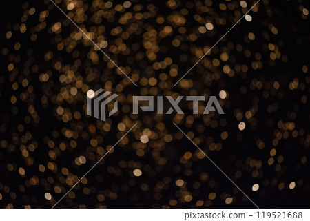 Golden blurry bokeh spots on a black background. Festive background. 119521688