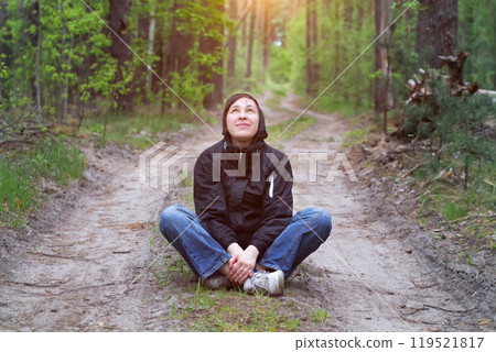 Man in the forest. A middle-aged woman sits on a forest road. Man in the forest. A middle-aged woman sits on a forest road. 119521817