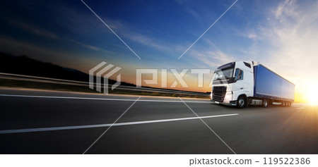 European truck driving on the asphalt road in rural landscape at sunset European truck driving on the asphalt road in rural landscape at sunset 119522386