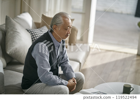 sad asian old man sitting alone on couch at home 119522494