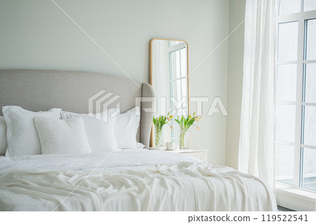 Stylish loft bedroom interior. Spacious design apartment with light walls large windows big bed. Clean modern decoration with elegant furniture in minimalist Scandinavian style Stylish loft bedroom interior. Spacious design apartment with light walls large windows big bed. Clean modern decoration with elegant furniture in minimalist Scandinavian style 119522541