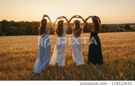 A group of women hold hands in a sunset field, embracing nature 119522643
