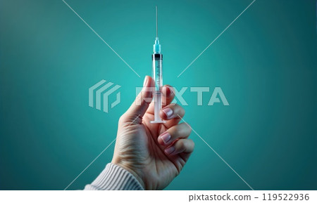 A person is firmly holding a medical syringe securely in their hand 119522936