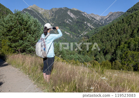 Young pretty tourist woman with backpack take a picture with mobil in the mountain 119523083