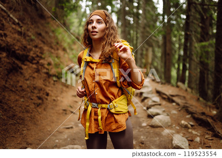 Traveler with yellow backpack walks along hiking path among mountains in the forest. Enjoys nature. 119523554