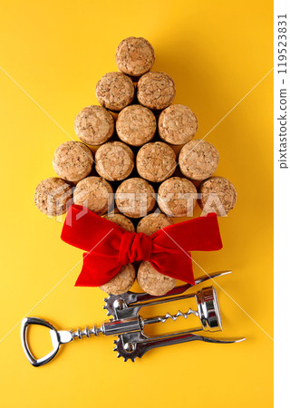 wine corks arranged in the shape of a Christmas tree and a metal corkscrew with a red bow on a yellow background wine corks arranged in the shape of a Christmas tree and a metal corkscrew with a red bow on a yellow background 119523831