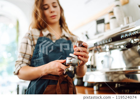 Woman bartender prepares a drink using a coffee machine in a cafe. Takeaway food. Woman bartender prepares a drink using a coffee machine in a cafe. Takeaway food. 119524074