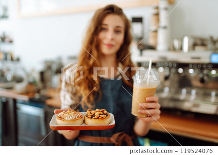 Woman barista holding takeaway coffee and dessert. Takeaway food and drink concept, small business. Woman barista holding takeaway coffee and dessert. Takeaway food and drink concept, small business. 119524076