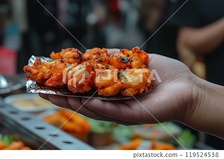 Hand holds colorful street food item in lively market crowd in the evening 119524538