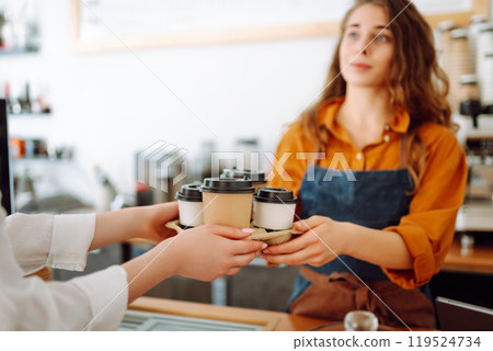 Close-up of a female barista's hands giving out a to-go drink order. Small business. Close-up of a female barista's hands giving out a to-go drink order. Small business. 119524734