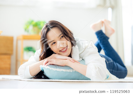 Smiling young woman lying down in the living room 119525063