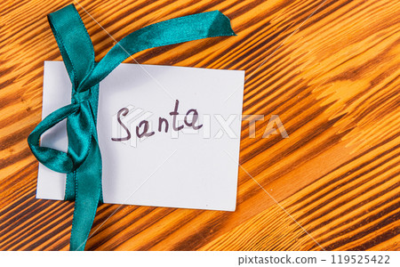 note to santa with green ribbon on wooden board, christmas concept note to santa with green ribbon on wooden board, christmas concept 119525422