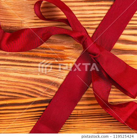 Dark red ribbon and bow on a beautiful wooden background Christmas concept 119525424