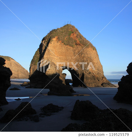 Rock formation with a cave at Wharariki Beach, New Zealand. Rock formation with a cave at Wharariki Beach, New Zealand. 119525579