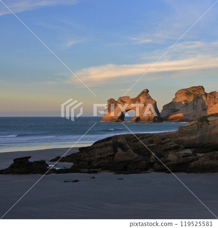 Arch shaped rock formation in golden evening light, Wharariki Beach. Arch shaped rock formation in golden evening light, Wharariki Beach. 119525581