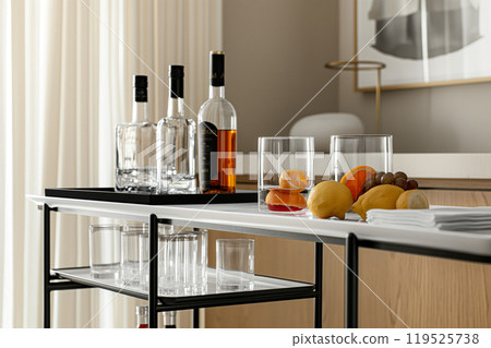 Elegant minimalist bar cart setup in a contemporary home interior with selective drinkware and bottles 119525738