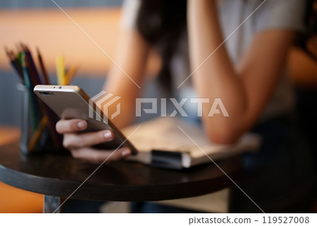 Asian teenage student woman using smartphone to surfing social media and entertainment for relaxation after studying and reading information in paperwork to learning about education knowledge in cafe Asian teenage student woman using smartphone to surfing social media and entertainment for relaxation after studying and reading information in paperwork to learning about education knowledge in cafe 119527008