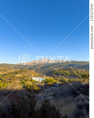 Breathtaking View of Sprawling Hills and Mountains Under a Clear Blue Sky During the Early Evening in a Serene Rural Landscape 119527344
