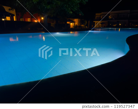 Tranquil Night by the Illuminated Poolside in a Cozy Resort Surrounded by Lush Trees and Soft Lighting 119527347
