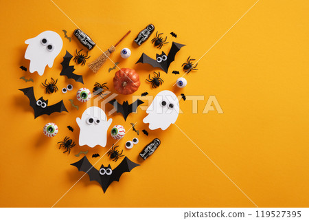 Halloween composition in the shape of a haunted heart, bats, pumpkins, spiders, eyeballs and a skeleton on a yellow background. A place for your text, invitation, advertisement. Halloween composition in the shape of a haunted heart, bats, pumpkins, spiders, eyeballs and a skeleton on a yellow background. A place for your text, invitation, advertisement. 119527395