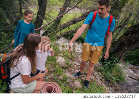 A joyful family joyously exploring the beauty of nature on a scenic hiking trail along with their young children A joyful family joyously exploring the beauty of nature on a scenic hiking trail along with their young children 119527717