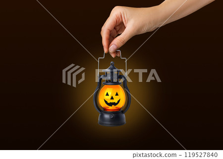 Halloween pumpkin lamp in a woman's hand. Halloween autumn concept. On black background Halloween pumpkin lamp in a woman's hand. Halloween autumn concept. On black background 119527840