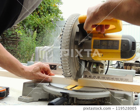 hands of a man working on a miter saw, sawing a wooden block on a miter saw, close-up, woodworking tool in action hands of a man working on a miter saw, sawing a wooden block on a miter saw, close-up, woodworking tool in action 119528005