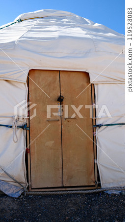 Traditional yurt entrance. Close-up of wooden door on nomadic tent dwelling against blue sky Traditional yurt entrance. Close-up of wooden door on nomadic tent dwelling against blue sky 119528083
