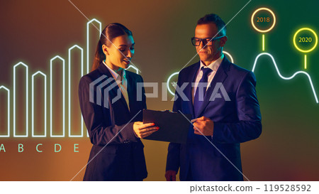 Presenter highlights growth and declines in market trends with colorful bar chart as backdrop. Presenter highlights growth and declines in market trends with colorful bar chart as backdrop. 119528592