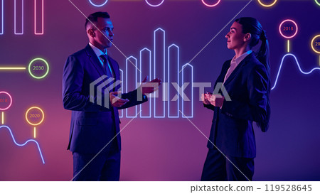 Tech-savvy professionals delivers dynamic presentation against neon lit screen with data analysis and insights. 119528645