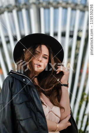 Portrait of an attractive woman in a pink dress and hat in an urban environment 119530298