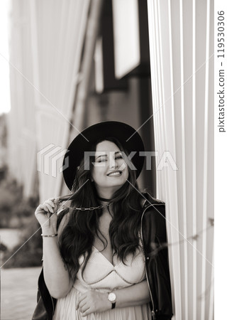 Portrait of an attractive woman in a pink dress and hat in an urban environment 119530306