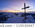 Majestic sunset over snowy mountain peak with cross silhouette, creating peaceful winter landscape 119530447