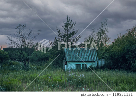 A small blue rustic house in a huge green field on a cloudy day A small blue rustic house in a huge green field on a cloudy day 119531151