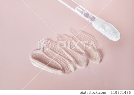 Shimmering nude lip gloss with applicator on pink background 119531486