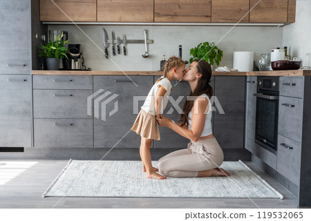 Mother and daughter sitting on kitchen floor and spending time together. Family bonding Mother and daughter sitting on kitchen floor and spending time together. Family bonding 119532065