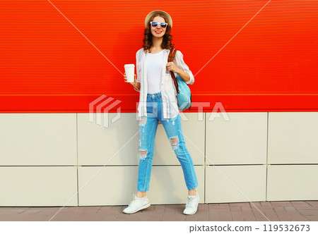 Young woman model posing wearing a casual, summer straw round hat on city street over red background 119532673