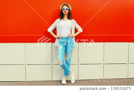 Young woman model posing wearing a casual, summer straw round hat on city street over red background Young woman model posing wearing a casual, summer straw round hat on city street over red background 119532675