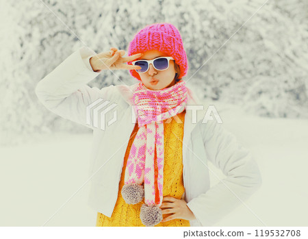 Fashion winter woman wearing a colorful knitted hat scarf having fun over snowy trees Fashion winter woman wearing a colorful knitted hat scarf having fun over snowy trees 119532708