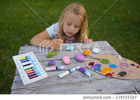 Child craft activities, girl paints heart on stones. Preschooler art work. Mother's day handmade present. 119533107