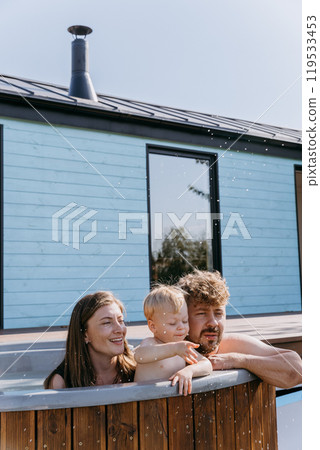 Happy family enjoying a relaxing time together in a hot tub on a sunny day, creating joyful memories Happy family enjoying a relaxing time together in a hot tub on a sunny day, creating joyful memories 119533453