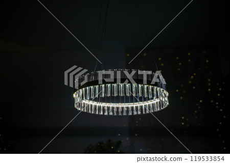 A large, clear, and shiny chandelier hangs from the ceiling. The light is on, illuminating the room. 119533854